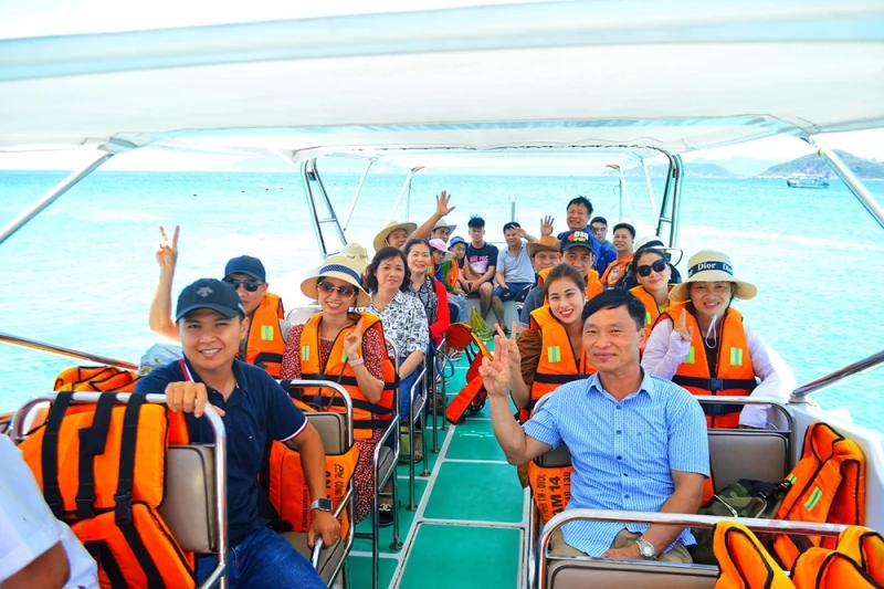 Đoàn du khách ngồi trên cano tham quan vịnh Nha Trang, bên cạnh các áo phao màu cam