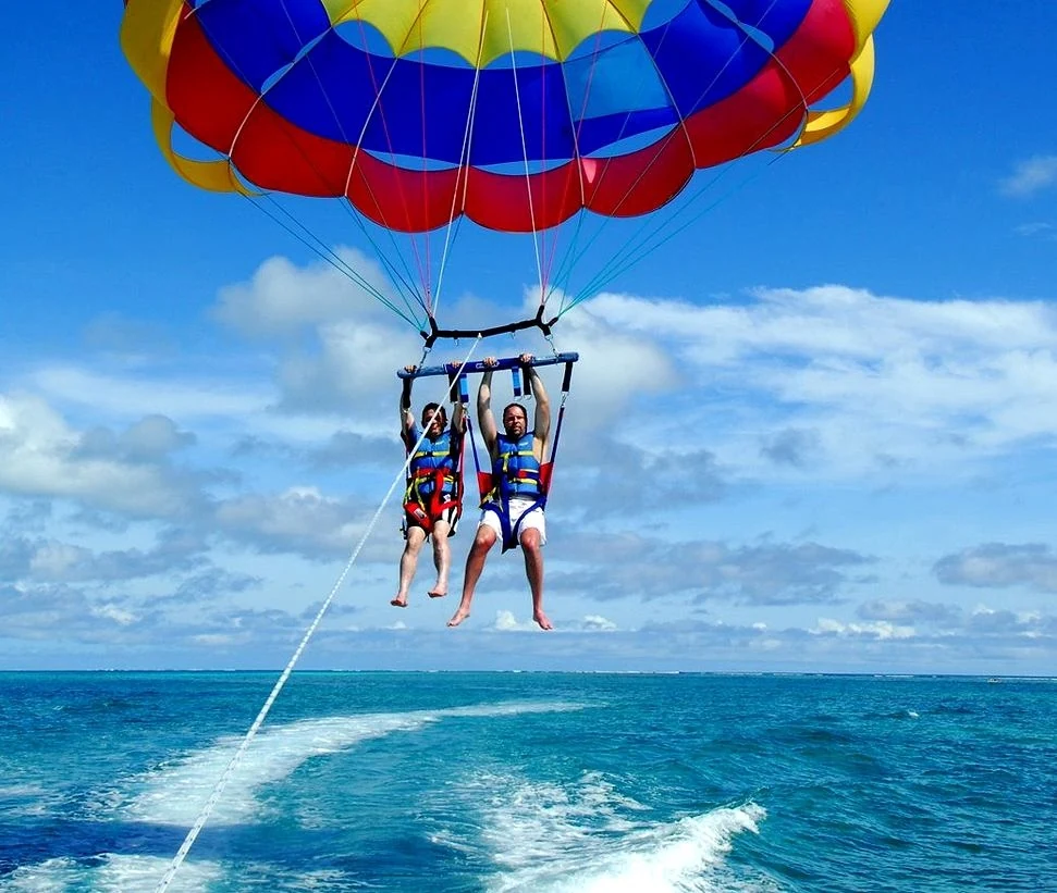 Hai du khách bay trên biển dưới chiếc dù nhiều màu