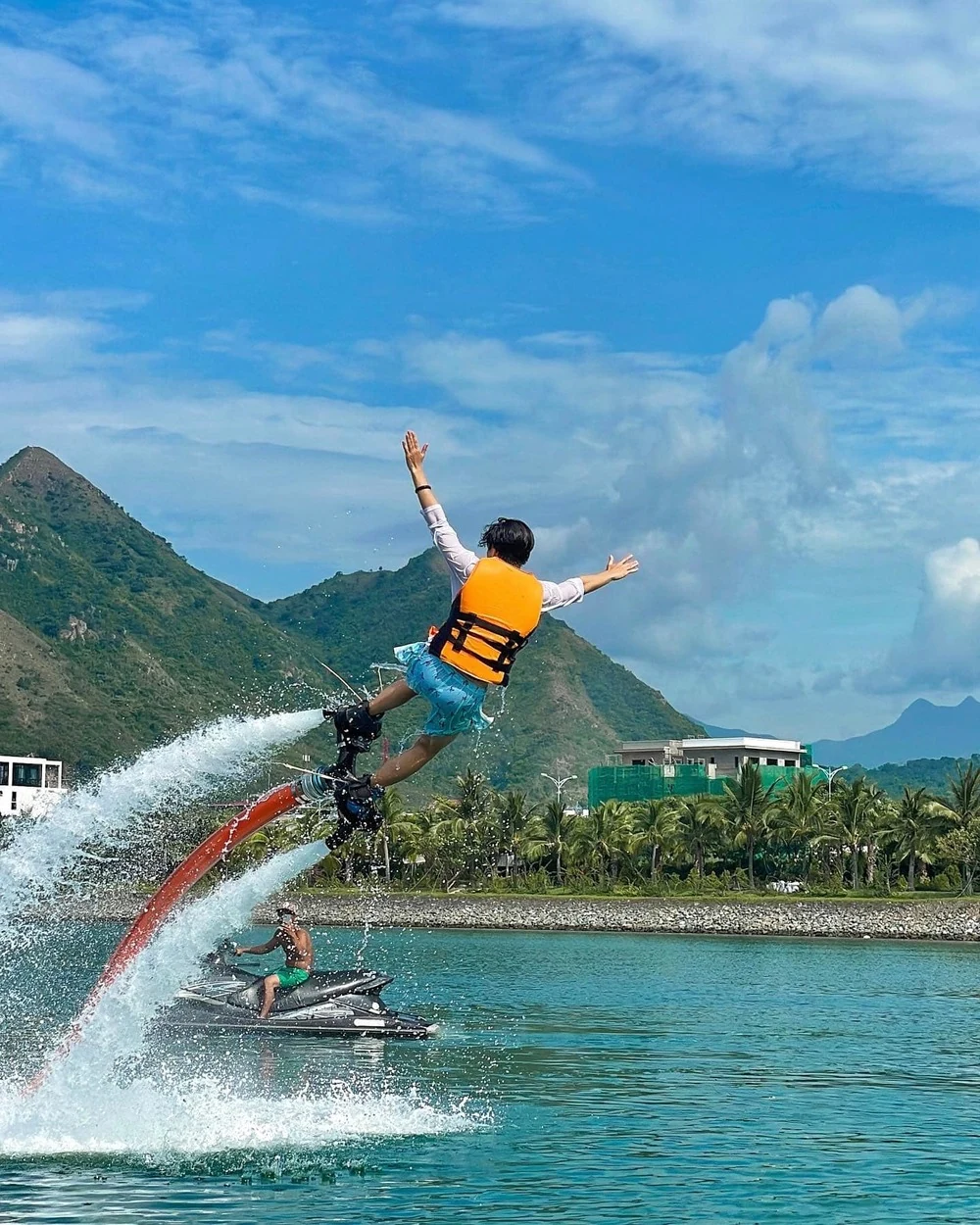 Người chơi mặc áo phao màu cam được lực nước nâng lên khi chơi Flyboard