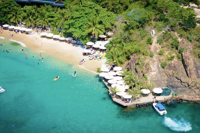 Bãi cát Mini Beach bên làn nước xanh với hàng dù trắng sát chân núi