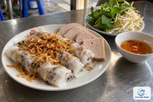 Đĩa bánh cuốn nhân thịt mộc nhĩ rắc hành phi, kèm chả lụa, rau thơm, giá và chén nước mắm pha, ảnh minh hoạ